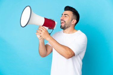 İzole edilmiş mavi arka planda beyaz bir adam megafondan bir şey duyurmak için bağırıyor.
