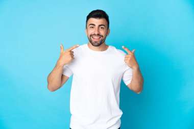 İzole edilmiş mavi arka planda beyaz bir adam baş parmak hareketi yapıyor.