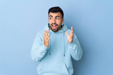 Yüzünde sürpriz ifade olan, izole edilmiş mavi arka planda beyaz bir adam.