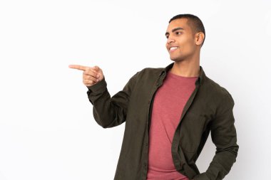 İzole edilmiş beyaz arka planda genç bir Afro-Amerikalı parmağını yana uzatarak bir ürün sunuyor.