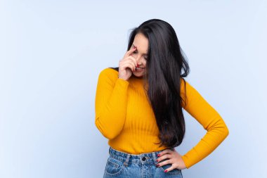 Genç Kolombiyalı kız mavi arka planda gülüyor.