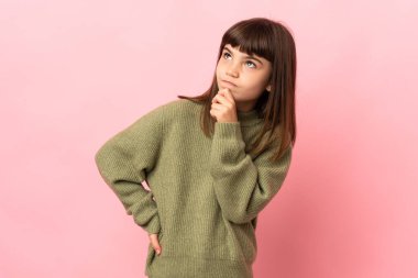 Küçük kız pembe arka planda izole edilmiş ve yukarı bakıyor.