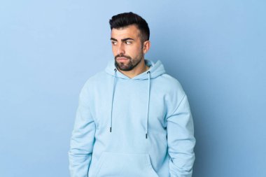 İzole edilmiş mavi arka planda beyaz bir adam şüpheli hareketler yapıyor.