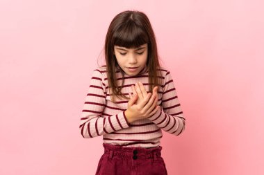 Pembe arka planda izole edilmiş küçük bir kız ellerinde acıdan kıvranıyor.