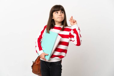 Beyaz arka planda izole edilmiş küçük öğrenci kız parmaklarını çapraz yapıp en iyisini diliyor.