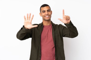 Genç Afro-Amerikalı adam izole edilmiş beyaz arka planda yediyi parmaklarıyla sayıyor