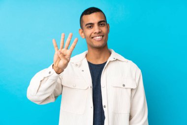 Genç Afro-Amerikalı adam mavi arka planda mutlu ve parmakları olan dört kişi sayıyor.