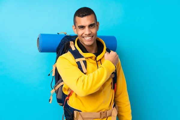 Junger Bergsteiger Mit Großem Rucksack Vor Isoliertem Blauen Hintergrund Feiert — Stockfoto