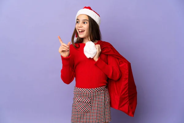 Kleines Mädchen Mit Hut Und Weihnachtssack Isoliert Auf Lila Hintergrund — Stockfoto