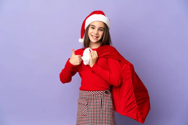 Kleines Mädchen Mit Hut Und Weihnachtssack Isoliert Auf Lila Hintergrund — Stockfoto