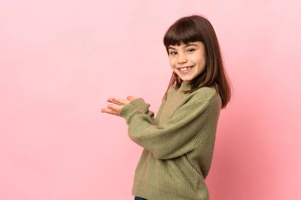 Menina Isolada Fundo Rosa Estendendo Mãos Para Lado Para Convidar — Fotografia de Stock