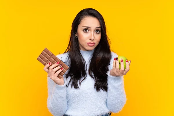 Junges Kolumbianisches Mädchen Auf Isoliertem Gelbem Hintergrund Mit Einer Schokoladentablette — Stockfoto