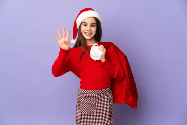 Kleines Mädchen Mit Hut Und Weihnachtssack Auf Lila Hintergrund Isoliert — Stockfoto