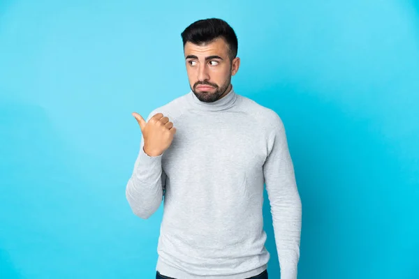 Homem Caucasiano Sobre Fundo Azul Isolado Infeliz Apontando Para Lado — Fotografia de Stock