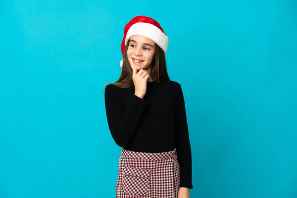 Klein Meisje Met Kerst Hoed Geïsoleerd Blauwe Achtergrond Kijken Naar — Stockfoto