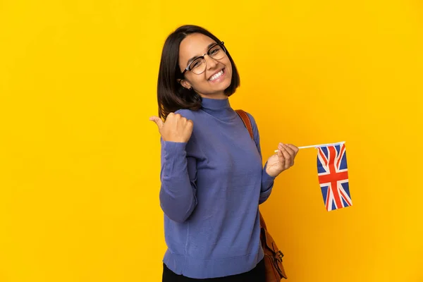 Młoda Latynoska Posiadająca Flagę Zjednoczonego Królestwa Odizolowaną Żółtym Tle Wskazującą — Zdjęcie stockowe