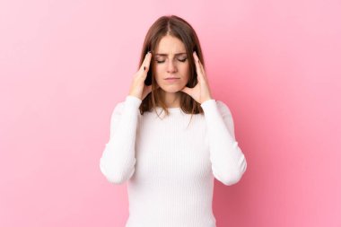 Soyutlanmış pembe arka planda baş ağrısı olan genç bir kadın.