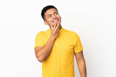 Genç Ekvadorlu adam beyaz arka planda izole edilmiş gülümserken yukarı bakıyor