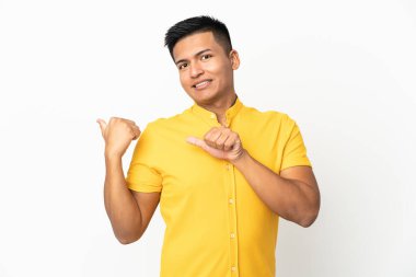 Beyaz arka planda izole edilmiş genç Ekvadorlu bir adam bir ürünü sunmak için yan tarafı işaret ediyor.