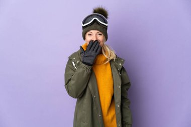 Skier Russian girl with snowboarding glasses isolated on purple background happy and smiling covering mouth with hand