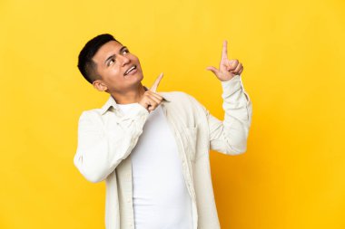 Genç Ekvadorlu adam sarı arka planda izole edilmiş işaret parmağıyla işaret etmek harika bir fikir.