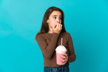 Mavi arka planda izole edilmiş çilekli milkshake 'i olan küçük bir kız şüpheleri var.