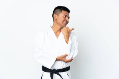 Beyaz arka planda karate yapan genç Ekvadorlu bir adam bir ürün sunmak için kenarı işaret ediyor.