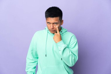 Genç Ekvadorlu adam mor arka planda izole edilmiş bir şey gösteriyor.