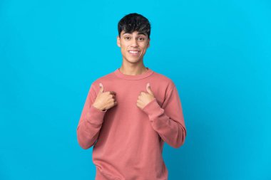 Soyutlanmış mavi arka planı olan genç bir adam. Şaşırtıcı bir yüz ifadesi.