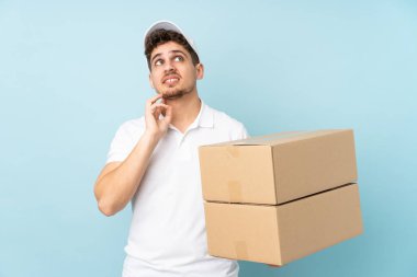 Teslimat yapan beyaz adam mavi arka planda izole edilmiş bir fikir düşünüyor.