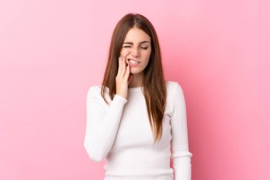 İzole edilmiş, pembe arka planda diş ağrısı olan genç bir kadın.
