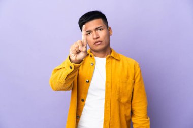 Genç Ekvadorlu, mor arka planda izole edilmiş, ciddi ifadeli birini sayıyor.