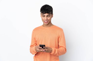 Young man over isolated white background sending a message with the mobile