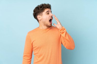 Caucasian man isolated on blue background yawning and covering wide open mouth with hand
