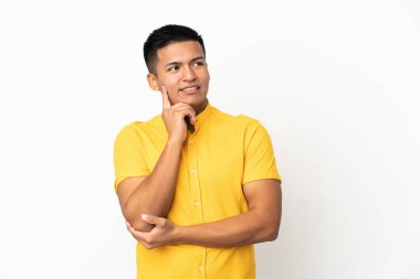 Genç Ekvadorlu bir adam beyaz arka planda izole edilmiş, yukarı bakarken bir fikir düşünüyor.