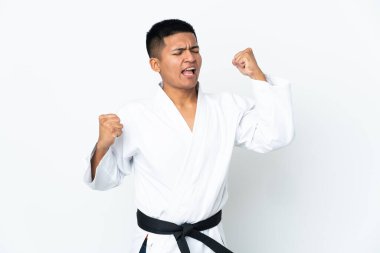Beyaz arka planda karate yapan genç Ekvadorlu bir adam zaferi kutluyor.