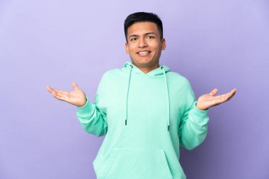 Genç Ekvador 'lu adam mor arka planda izole edilmiş ve şok olmuş yüz ifadesi var.