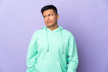Genç Ekvadorlu adam mor arka planda izole edilmiş. Taraf ararken şüphe duyuyor.