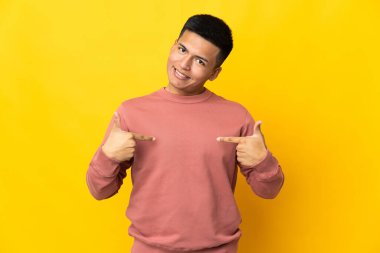 Genç Ekvadorlu adam sarı arka planda soyutlanmış gururlu ve kendini beğenmiş.