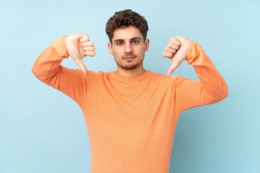 Caucasian man isolated on blue background showing thumb down