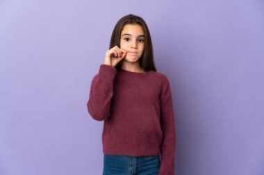 Mor arka planda izole edilmiş küçük bir kız sessizlik işareti gösteriyor.