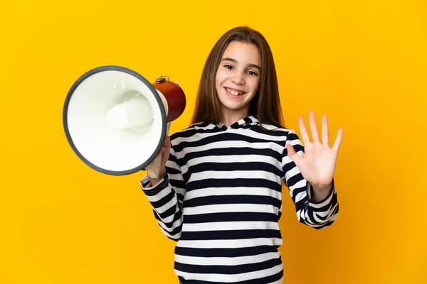 Little Girl Isolated Yellow Background Holding Megaphone Saluting Hand Happy — Stok fotoğraf