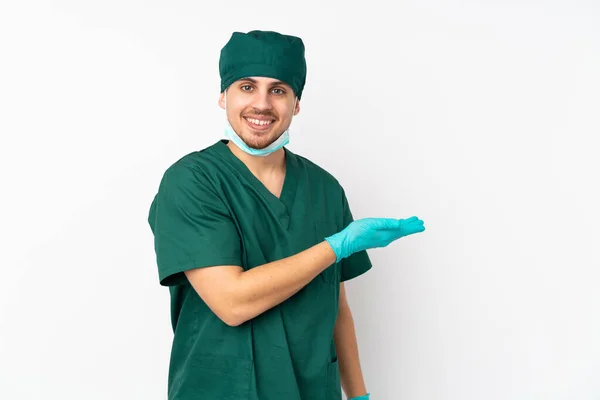 身穿绿色制服的外科医生被隔离在孤立的白色背景下 带着一种想法 面带微笑地看着 — 图库照片
