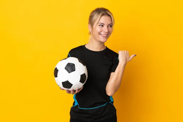 製品を提示する側を指して黄色の背景に隔離された若いロシアのサッカー選手の女性 — ストック写真