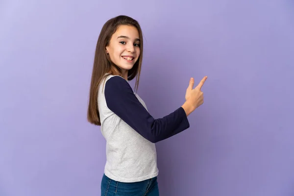 Little Girl Isolated Purple Background Pointing Back — Stock Photo, Image