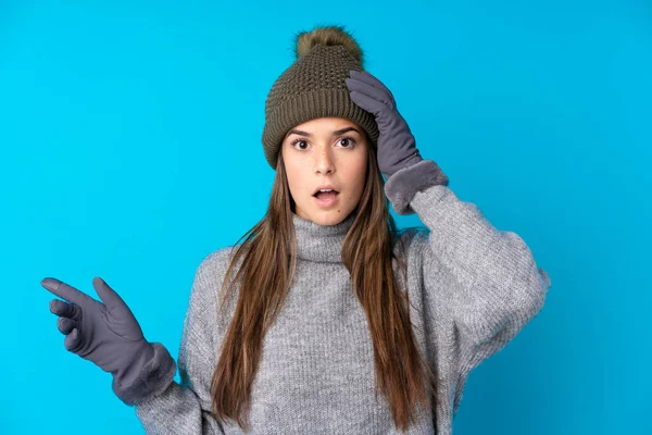 Kışlık Şapkalı Genç Kız Mavi Arka Planda Kaldı Şaşırdı Işaret — Stok fotoğraf