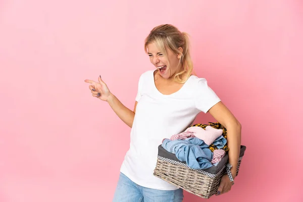 Young Russian Woman Holding Clothes Basket Isolated Pink Background Pointing — Stok fotoğraf