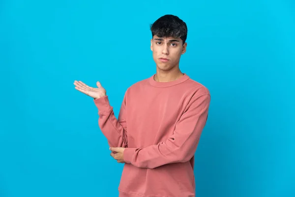 Jovem Sobre Fundo Azul Isolado Com Dúvidas — Fotografia de Stock