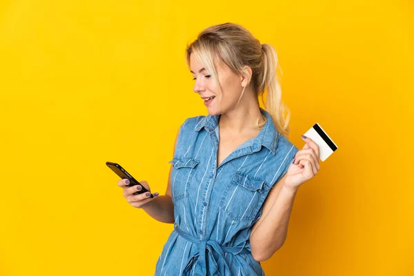 Jonge Russische Vrouw Geïsoleerd Gele Achtergrond Kopen Met Mobiele Telefoon — Stockfoto