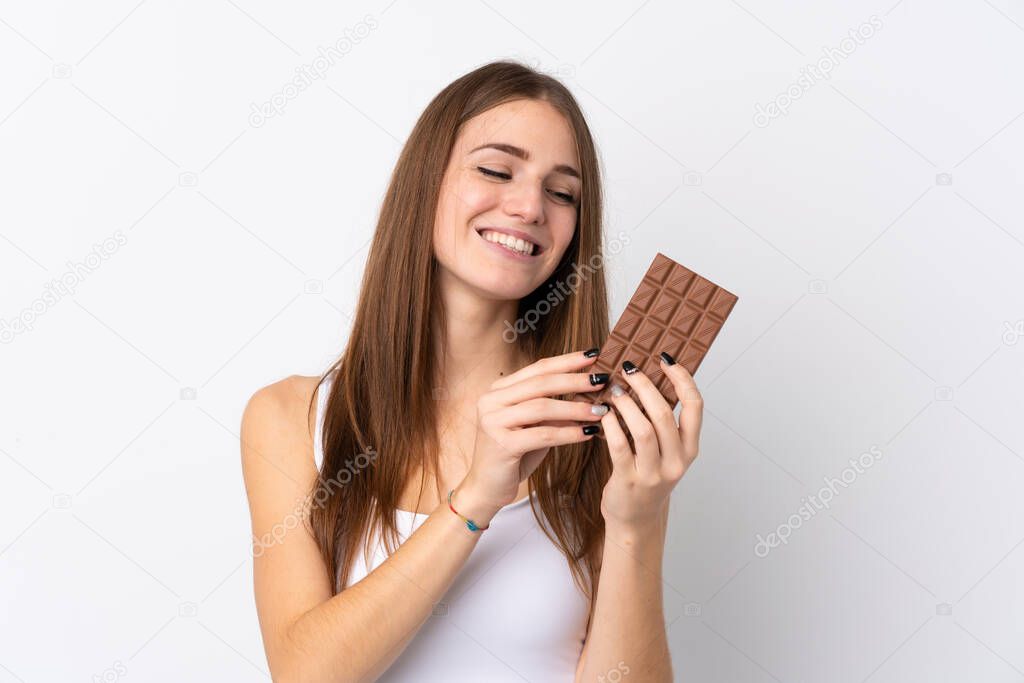Young woman over isolated white background taking a chocolate tablet and happy